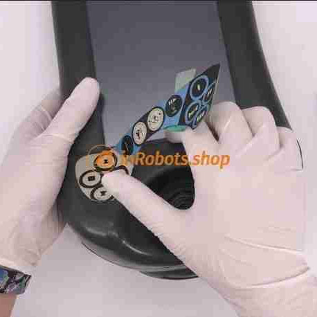 An electronics technician peeling back a damaged teach pendant membrane keypad to inspect worn conductive silver traces and moisture corrosion causing ghost keys and button failure.
